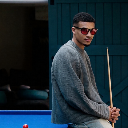 Man in glasses holding a pool cue next to a pool table with pool balls