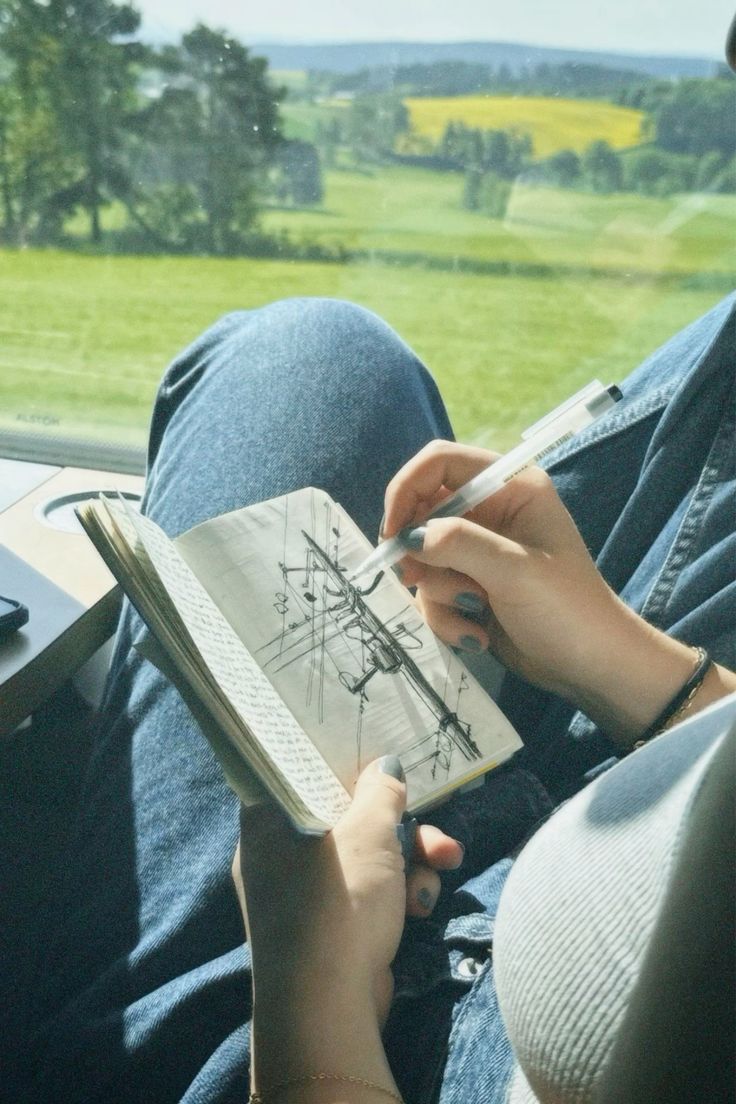 Writing in a black pocket journal during a train journey