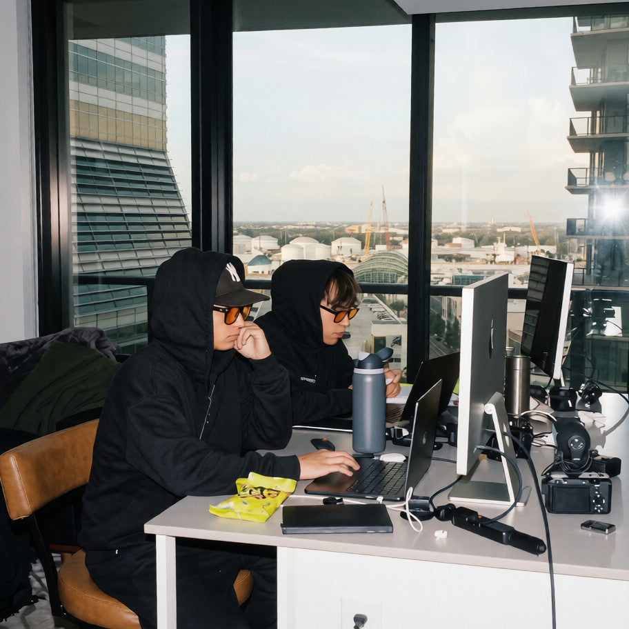 Two people wearing orange day blue light blocking glasses working at computers in an office