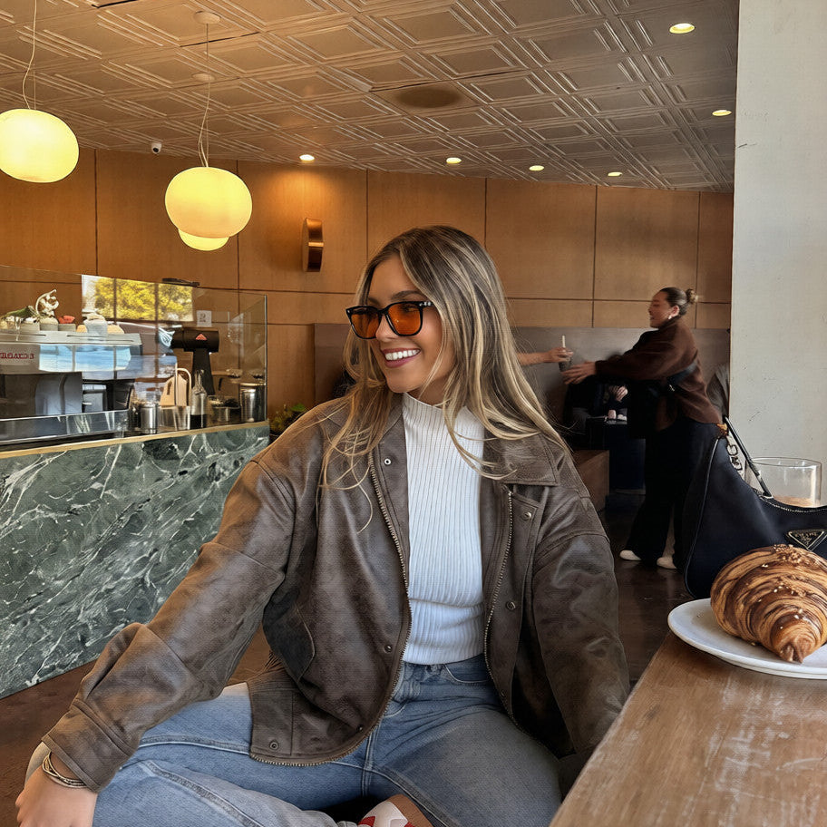 Girl sitting in a cafe with orange day blue light blocking glasses on